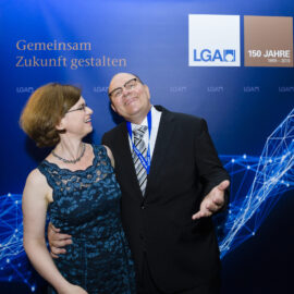 Das Bild zeigt zwei Personen, die vor einem blauen Hintergrund posieren. Auf dem Hintergrund steht der Schriftzug „Gemeinsam Zukunft gestalten“ sowie das LGA Logo 150 Jahre