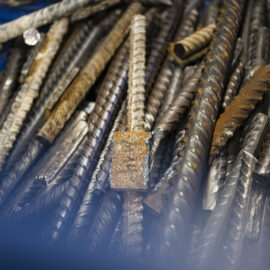 Auf dem Bild sind zahlreiche Stahlstäbe und Metallproben zu sehen, die in einem Behälter gesammelt wurden. Die unterschiedlich geformten und teilweise korrodierten Metallteile liegen dicht übereinander und zeigen verschiedene Oberflächenstrukturen. Die Aufnahme konzentriert sich auf die Materialien und vermittelt den Eindruck einer technischen Untersuchung oder Materialprüfung.