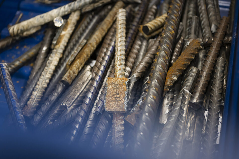 Auf dem Bild sind zahlreiche Stahlstäbe und Metallproben zu sehen, die in einem Behälter gesammelt wurden. Die unterschiedlich geformten und teilweise korrodierten Metallteile liegen dicht übereinander und zeigen verschiedene Oberflächenstrukturen. Die Aufnahme konzentriert sich auf die Materialien und vermittelt den Eindruck einer technischen Untersuchung oder Materialprüfung.