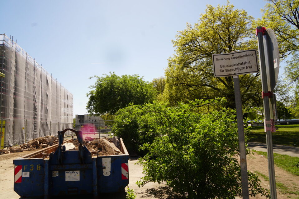 Baustellenzufahrt zur Sanierung der Zeppelintribüne mit Baucontainer, Gerüst und Hinweisschild „Baustellenzufahrt für Berechtigte frei“.