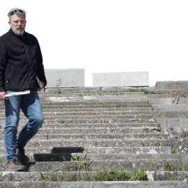 Sachverständiger auf den Stufen der Zeppelintribüne bei einer Bauwerksbegehung mit Messlatte in der Hand. Freigestellt, ohne Hintergrund.