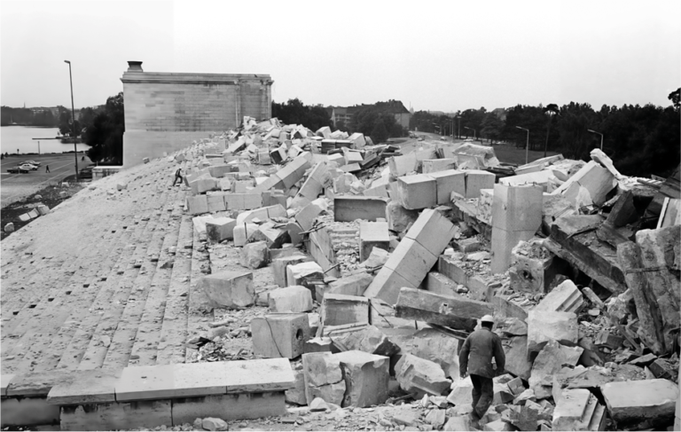 Historische Aufnahme der gesprengten Haupttribüne des Zeppelinfelds mit großen Trümmerblöcken nach dem Ende des Zweiten Weltkriegs.