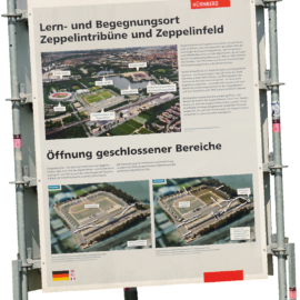 Informationsschild zum Lern- und Begegnungsort Zeppelintribüne und Zeppelinfeld mit Übersichtsplan sowie Darstellung der geplanten Öffnung bisher geschlossener Bereiche.