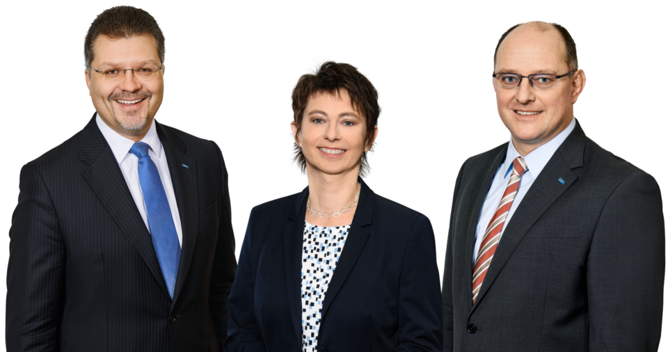 Drei Personen in formeller Businesskleidung stehen zusammen.