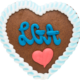 Ein Lebkuchenherz mit weißer Zuckerglasur am Rand liegt im Bildzentrum. In der Mitte befinden sich ein rotes Herz und ein Schriftzug aus blauer Zuckerschrift.