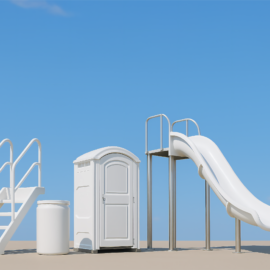 Das Bild zeigt eine weiße Rutsche und einer Treppe. Daneben stehen ein mobiles Toilettenhäuschen und ein Behälter, im Hintergrund ist ein klarer blauer Himmel zu sehen.