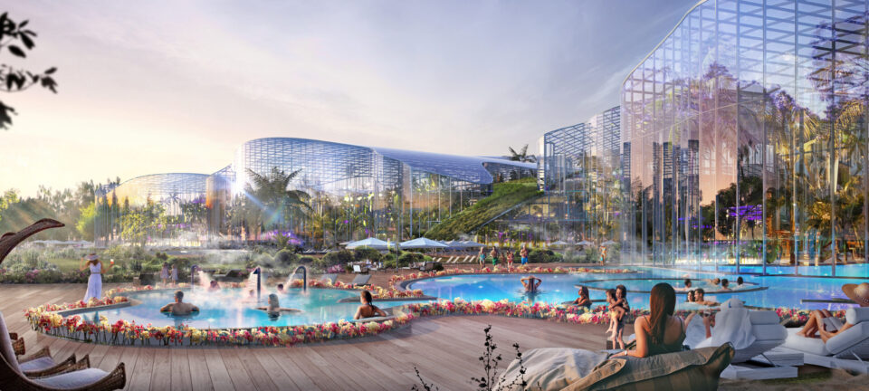 Das Bild zeigt eine luxuriöse Freizeitanlage mit mehreren Pools, umgeben von üppigem Grün und moderner Architektur. Menschen entspannen im Wasser und auf Liegestühlen, während im Hintergrund große verglaste Gebäude mit Pflanzen auf eine Gewächshaus- oder Gartenlandschaft hinweisen.
