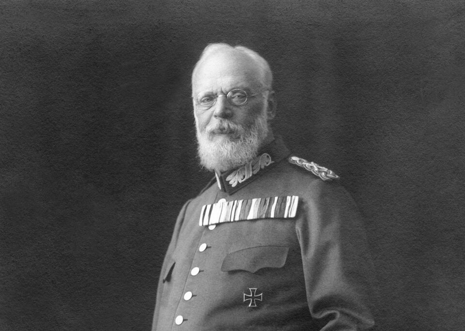 Das Bild zeigt eine historische Person in Militäruniform. Auf der Brust sind mehrere Orden und Auszeichnungen zu sehen, darunter ein Eisernes Kreuz.