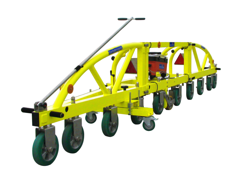 Das Bild zeigt ein gelbes, mehrrädriges Bau- oder Wartungsgerät. Das Gerät besitzt mehrere grüne Räder und scheint für Arbeiten an der Straße eingesetzt zu werden.