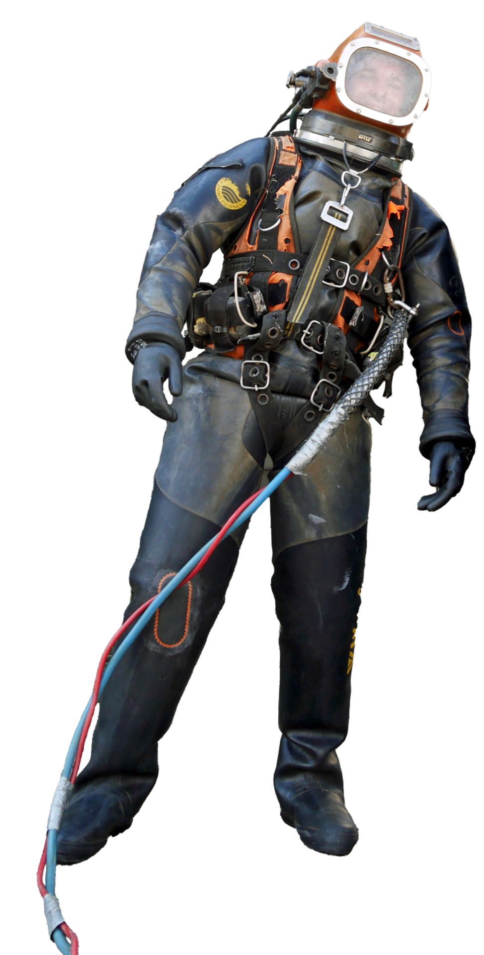 Das Bild zeigt eine Person in einem Tiefseetauchanzug mit Helm und Sichtfenster. Der Anzug ist mit mehreren Gurten, Schnallen und Schläuchen ausgestattet, die in Rot, Blau und Weiß gehalten sind. Die Person hält oder ist mit diesen Kabeln verbunden.