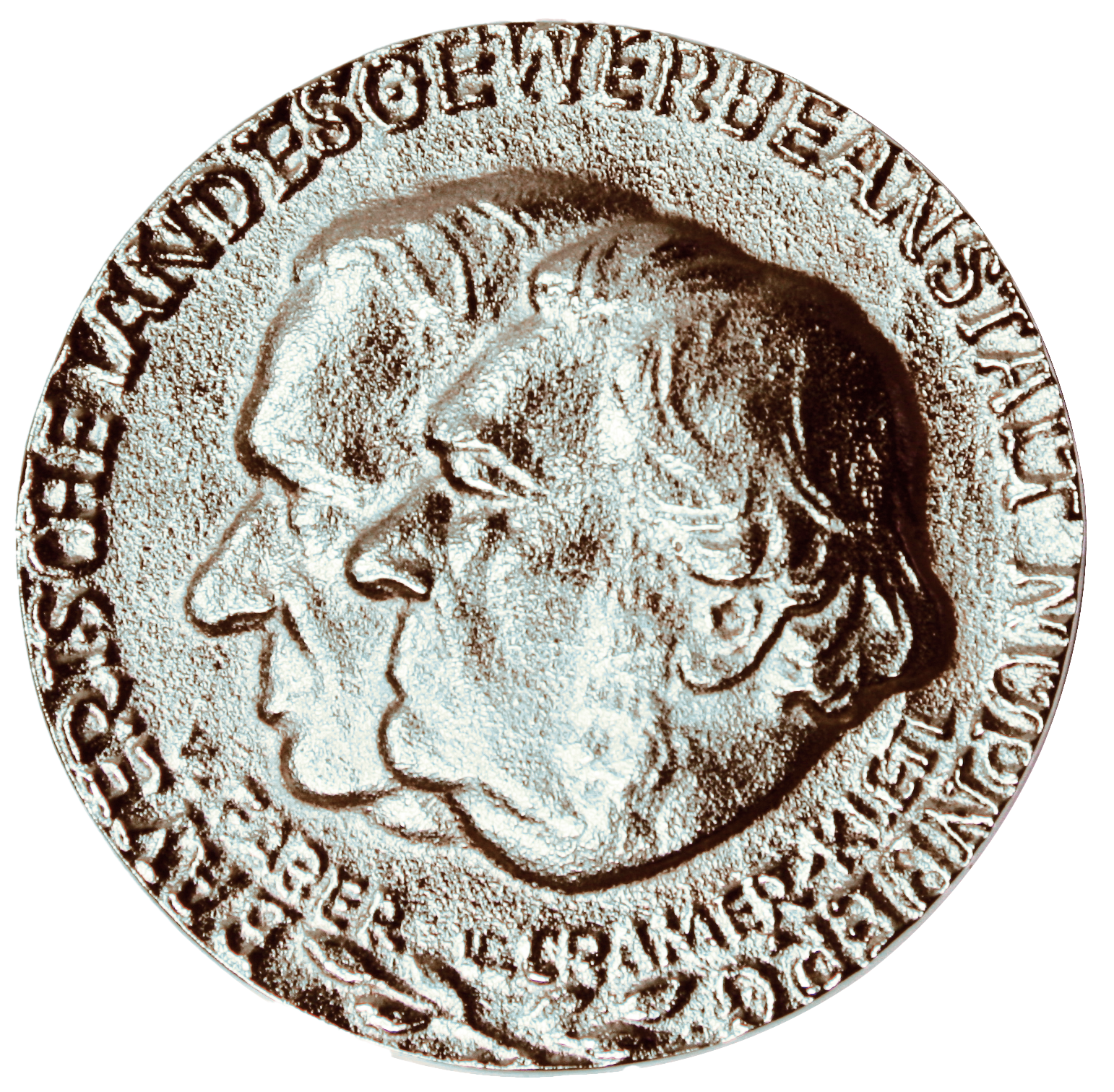 Das Bild zeigt eine silberne Medaille mit den geprägten Profilen zweier Köpfe in der Mitte. Am Rand der Münze verläuft eine Inschrift in Großbuchstaben.