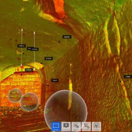 Das Bild zeigt eine 3D-Scan-Darstellung einer unterirdischen oder höhlenartigen Struktur mit farblicher Tiefenanzeige von Blau (flach) bis Rot (tief). Innerhalb der Darstellung sind mehrere Maßangaben in Metern zu sehen. Am unteren Bildrand befinden sich Symbole für Werkzeuge und Einstellungen der Scan-Visualisierung.