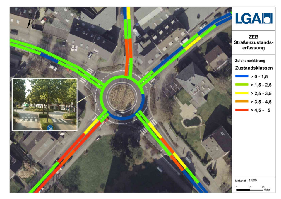 Das Bild zeigt eine Luftaufnahme eines Kreisverkehrs mit farblich markierten Straßenabschnitten, die unterschiedliche Straßenzustandsklassen darstellen. Rechts im Bild befindet sich eine Legende mit den Farbcodes sowie ein Maßstabsbalken. Zusätzlich ist ein kleines Bildausschnitt mit einer Straßenansicht und einem Zebrastreifen zu sehen.