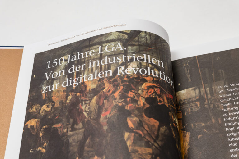 Das Bild zeigt ein aufgeschlagenes Buch mit einer Illustration und Text auf der linken Seite. Der Text lautet: 150 Jahre LGA. Von der industriellen zur digitalen Revolution. Die rechte Seite ist nicht vollständig sichtbar.