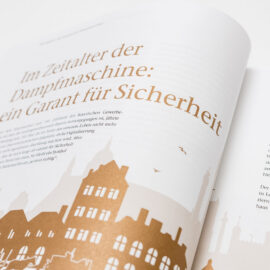 Das Bild zeigt ein aufgeschlagenes Buch mit einem Text in deutscher Sprache und einer Grafik einer Stadt-Skyline in Bronzetönen. Der Text beschreibt die Rolle neuer Verkehrsmittel im Zeitalter der Dampfmaschine und deren Bedeutung für Sicherheit und Fortschritt.