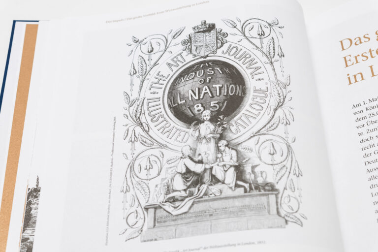 Das Bild zeigt eine Seite aus einem Buch oder Magazin mit einer Illustration unter dem Titel „THE ART JOURNAL ILLUSTRATED CATALOGUE“. Im Zentrum befindet sich ein großes rundes Emblem mit der Aufschrift „THE INDUSTRY OF ALL NATIONS 1851“, umgeben von dekorativen Elementen. Darunter sind drei Figuren dargestellt: eine stehende Figur in der Mitte und zwei sitzende Figuren zu beiden Seiten.