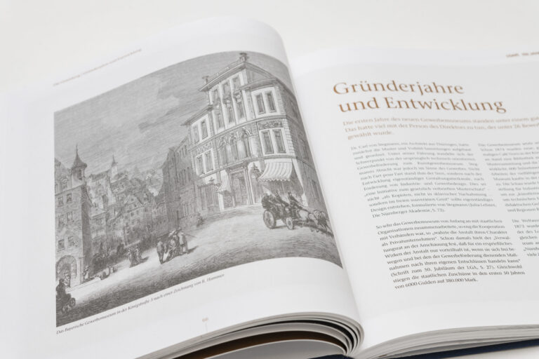 Das Bild zeigt ein aufgeschlagenes Buch mit einer Schwarz-Weiß-Zeichnung auf der linken Seite, die eine historische Straßenszene mit Gebäuden, Pferdekutschen und Menschen darstellt. Die Bildunterschrift verweist auf das Bayerische Gewerbemuseum. Auf der rechten Seite befindet sich ein Text mit dem Titel „Gründerjahre und Entwicklung“.