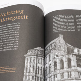 Das Bild zeigt ein geöffnetes Buch mit deutschem Text und einer schwarz-weißen Fotografie eines beschädigten Gebäudes. Der Text behandelt den Zweiten Weltkrieg und die Nachkriegszeit in Nürnberg. Die Fotografie zeigt Gebäuderuinen als Folge der Zerstörung im Krieg.