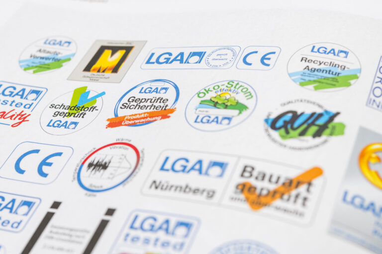 Das Bild zeigt eine Sammlung verschiedener Prüf- und Qualitätssiegel. Zu sehen sind unter anderem Symbole für Produktsicherheit, Schadstoffprüfung, Recycling, Ökostrom und CE-Kennzeichnung. Die Gestaltung umfasst unterschiedliche Farben und Formen der Siegel.