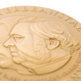 Anschnitt goldene Medaille mit zwei geprägten Profilen.