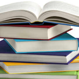 Ein Stapel aus sieben Büchern mit unterschiedlich farbigen Einbänden, wobei das oberste Buch geöffnet ist;